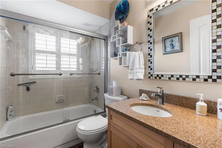 Bathroom with vanity and combined bath / shower with glass door