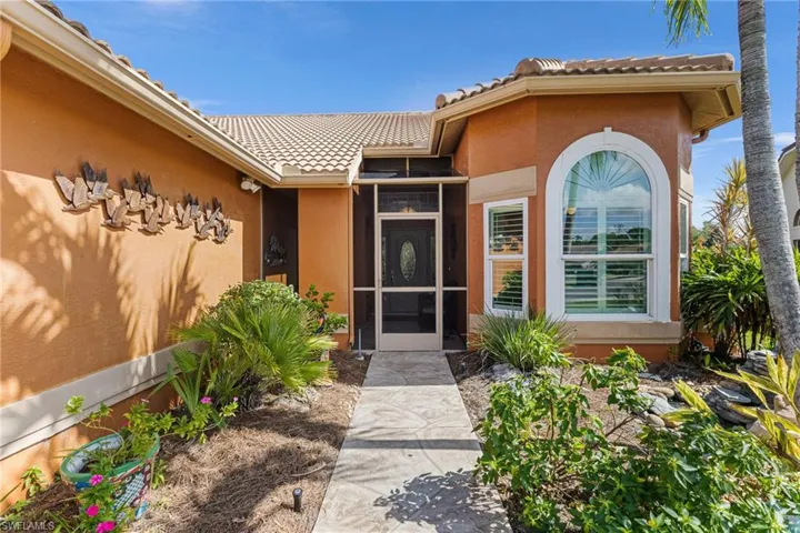 View of exterior entry with a tile roof and stucco siding