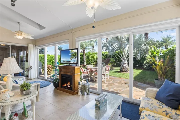 Living area with ceiling fan, light tile patterned floors, and a lit fireplace