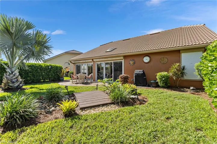 Back of property featuring a lawn, a tiled roof, and stucco siding