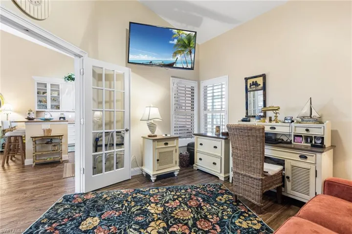 Office area with high vaulted ceiling and dark wood-style flooring