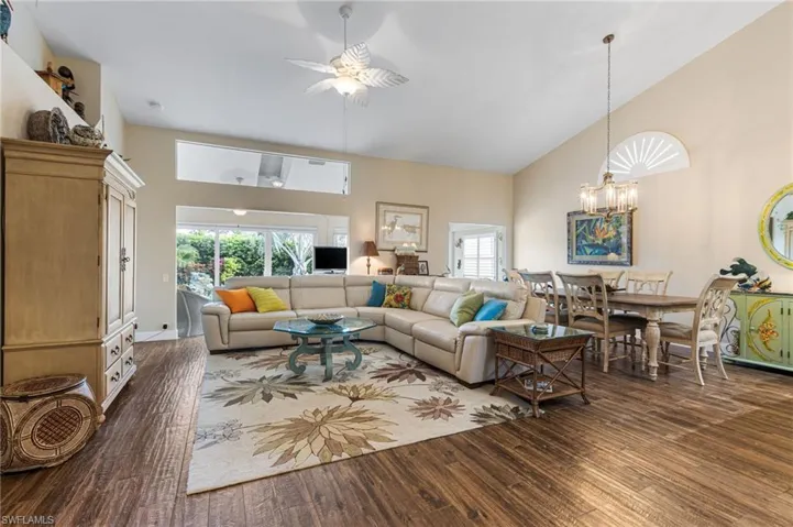 Living room with high vaulted ceiling, wood finished floors, a ceiling fan, and a chandelier