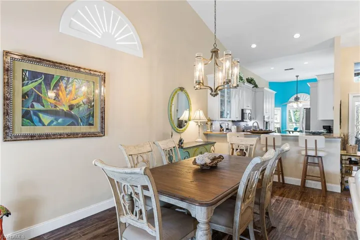 Dining space featuring dark wood-style floors, a chandelier, recessed lighting, and vaulted ceiling