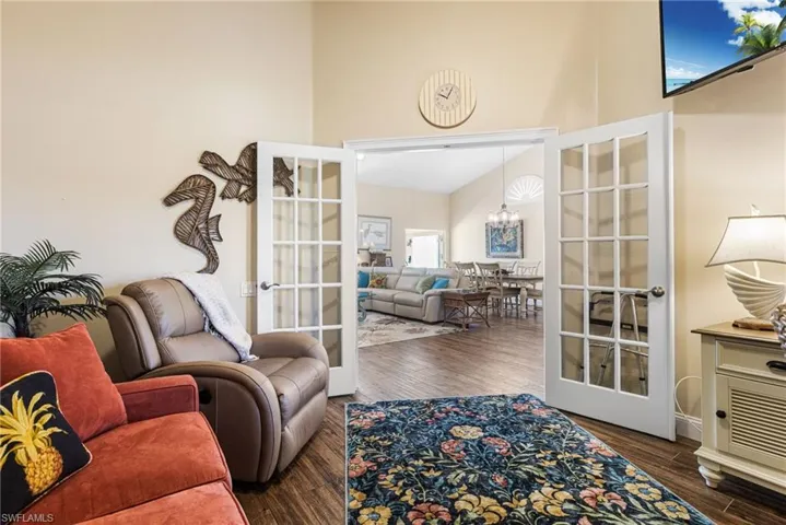 Living area with french doors, a high ceiling, wood finished floors, and a chandelier