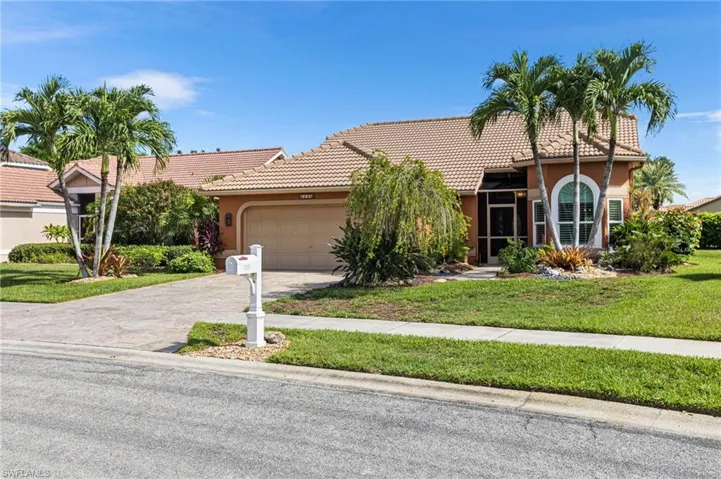 View of front of property featuring a tiled roof, a garage, driveway, and a front lawn