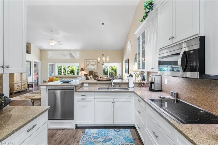 Kitchen with a peninsula, open floor plan, appliances with stainless steel finishes, glass insert cabinets, and white cabinets