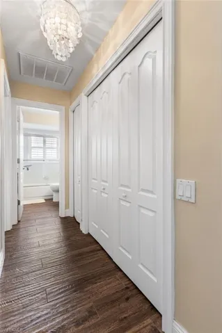 Hallway featuring a chandelier and dark wood-style floors