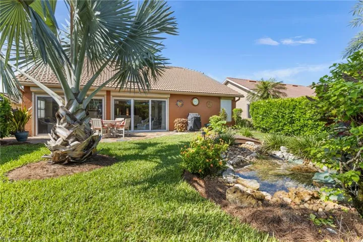 Back of house featuring a lawn, stucco siding, a tiled roof, and a patio