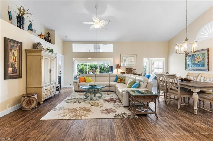 Living room with high vaulted ceiling, a chandelier, dark wood finished floors, and a ceiling fan