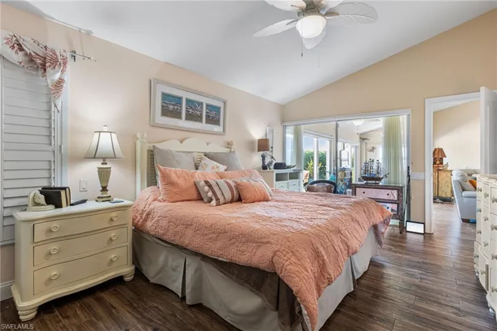 Bedroom featuring vaulted ceiling, access to outside, dark wood-type flooring, and a ceiling fan