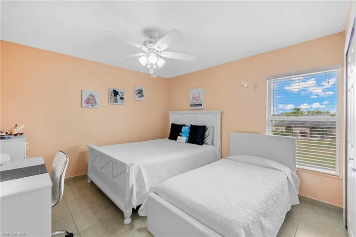 Bedroom with light tile patterned floors, baseboards, and a ceiling fan
