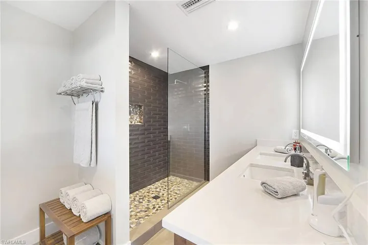 Primary bath with custom vanity, LED mirror, & top level tile in shower