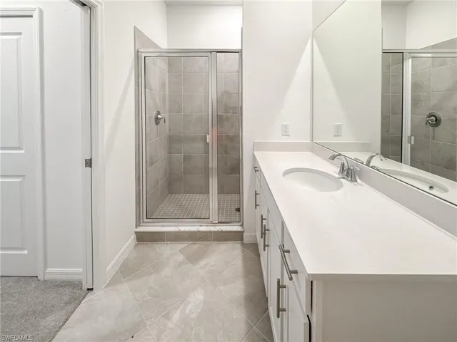 Full bathroom featuring a shower stall, vanity, and baseboards