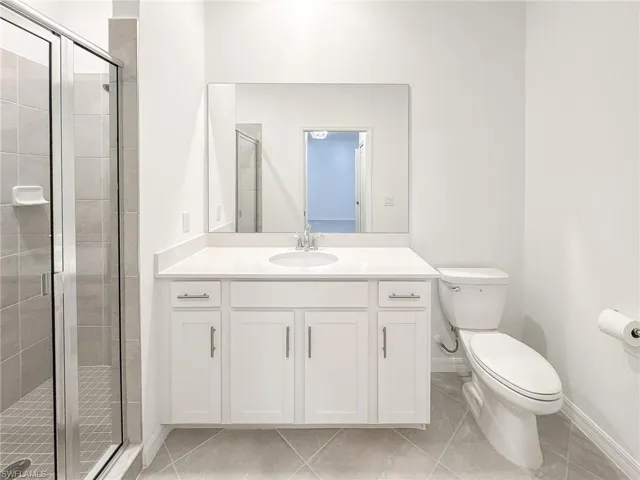 Full bathroom with a stall shower, baseboards, toilet, and vanity