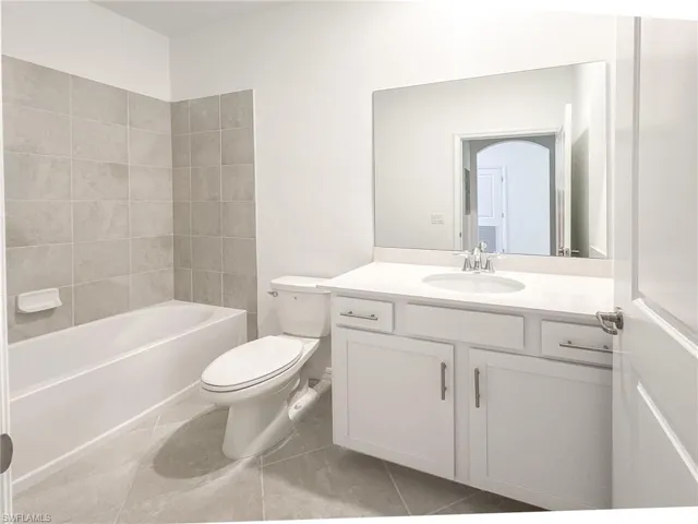 Bathroom with toilet, tile patterned floors, vanity, and  shower combination