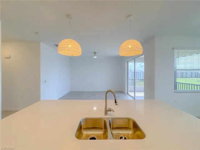 Kitchen with a sink, light countertops, decorative light fixtures, and ceiling fan