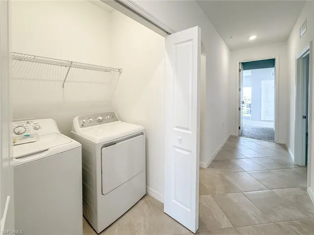 Laundry area with separate washer and dryer, baseboards, and light tile patterned floors