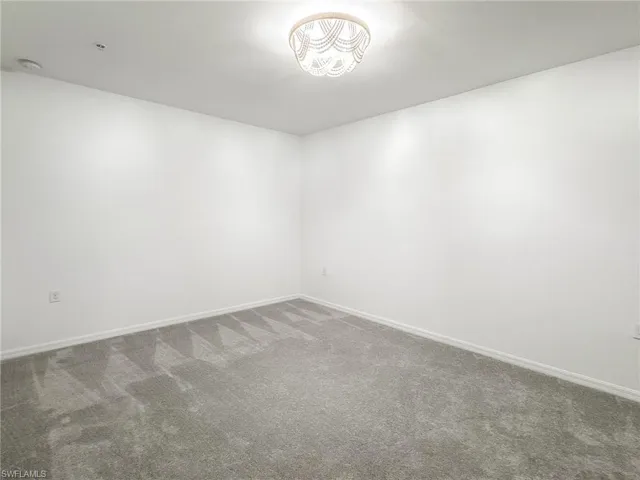 Spare room featuring carpet floors, baseboards, and a smoke detector