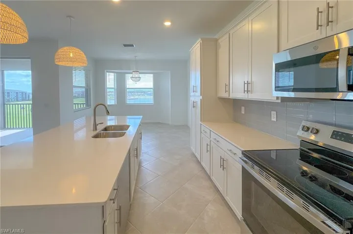 Kitchen with appliances with stainless steel finishes, a sink, backsplash, light countertops, and white cabinets