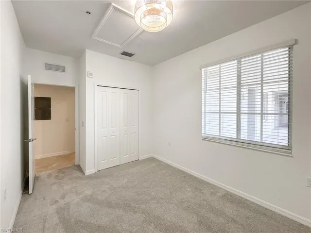 Unfurnished bedroom with light carpet, a closet, and baseboards