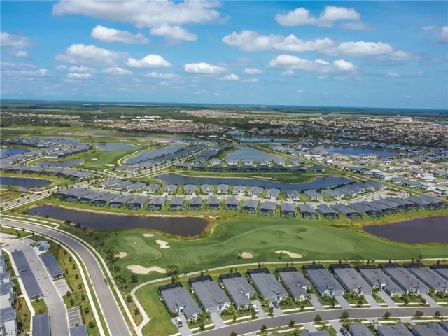 Aerial overview of property's location featuring nearby suburban area, a large body of water, and a local golf course