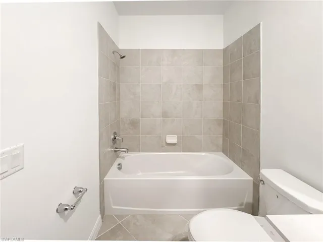Bathroom featuring toilet,  shower combination, and tile patterned floors