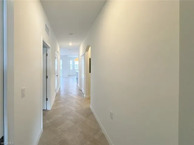 Corridor featuring baseboards and arched walkways