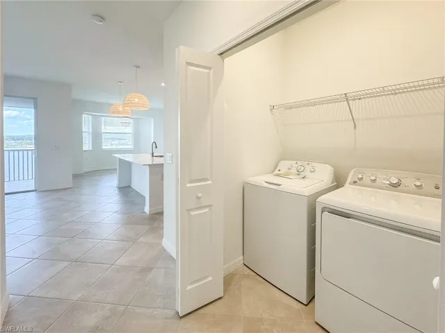 Laundry room with independent washer and dryer, baseboards, and light tile patterned floors