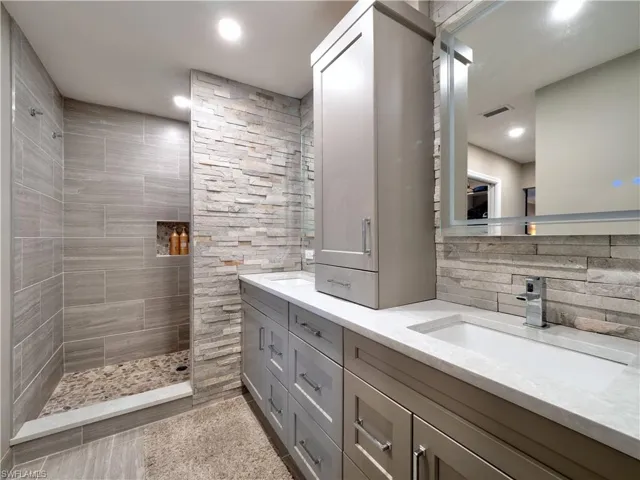 Bathroom featuring tasteful backsplash, vanity, and tiled shower