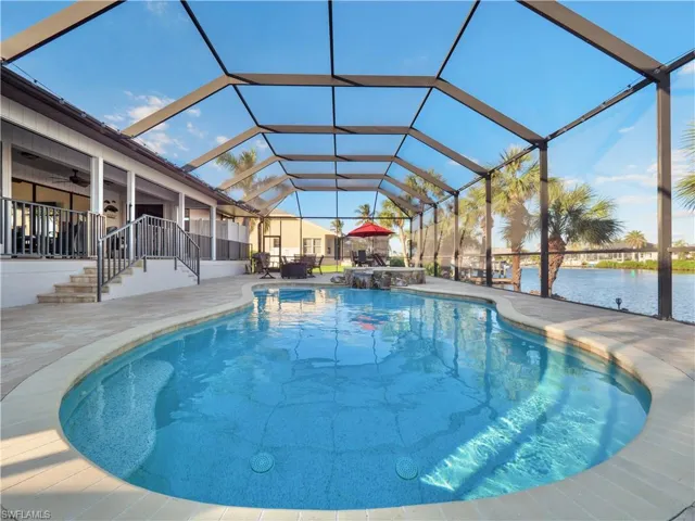 View of swimming pool with a lanai, ceiling fan, a water view, and a patio