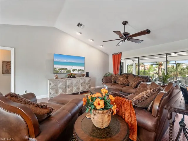 Living room with ceiling fan, wood-type flooring, and lofted ceiling