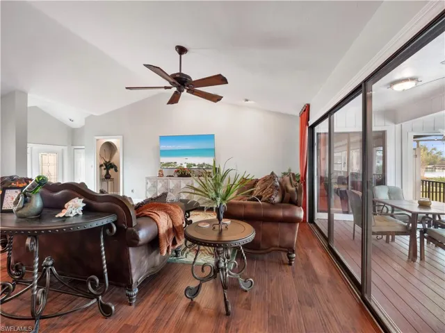 Living room with ceiling fan, lofted ceiling, and dark wood-type flooring