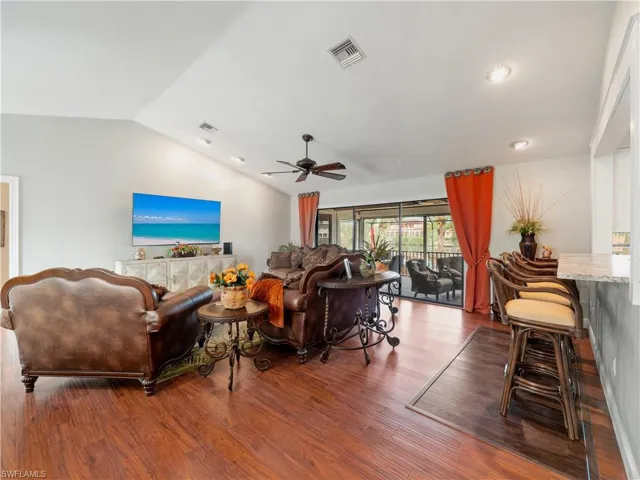 Living room featuring hardwood / wood-style floors, vaulted ceiling, and ceiling fan