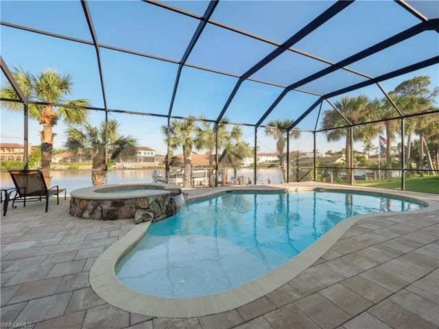 View of pool featuring a lanai, an in ground hot tub, a water view, and a patio