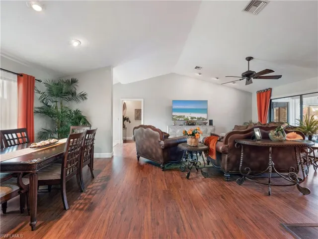 Living room featuring dark hardwood / wood-style flooring, a wealth of natural light, lofted ceiling, and ceiling fan