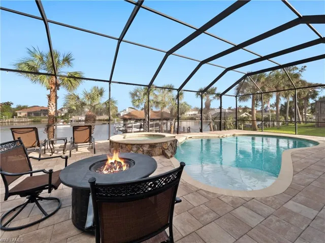 View of pool with a lanai, a patio area, an in ground hot tub, and a fire pit