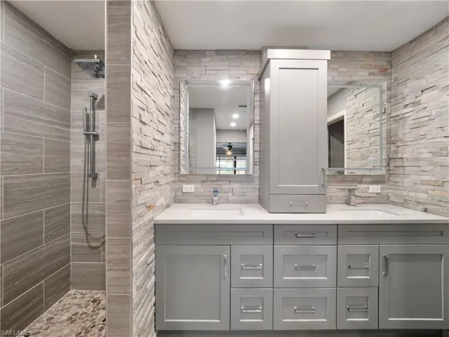 Bathroom with vanity, decorative backsplash, and tiled shower