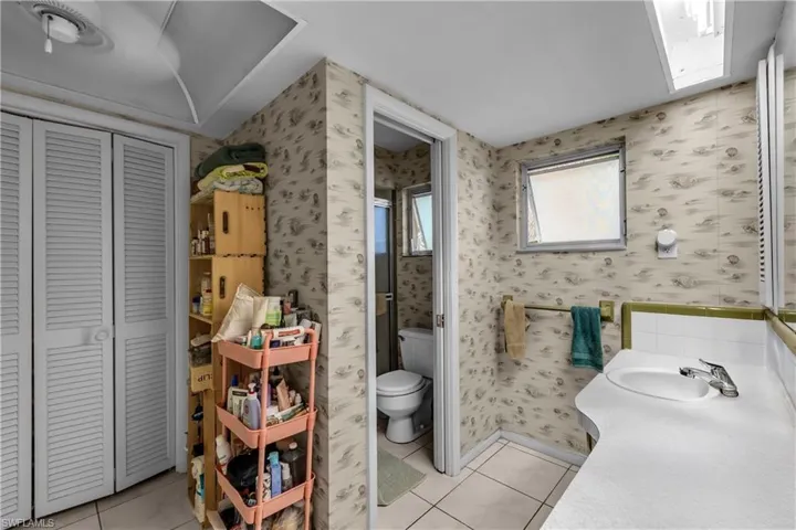 Full bath featuring wallpapered walls, a closet, vanity, and light tile patterned floors
