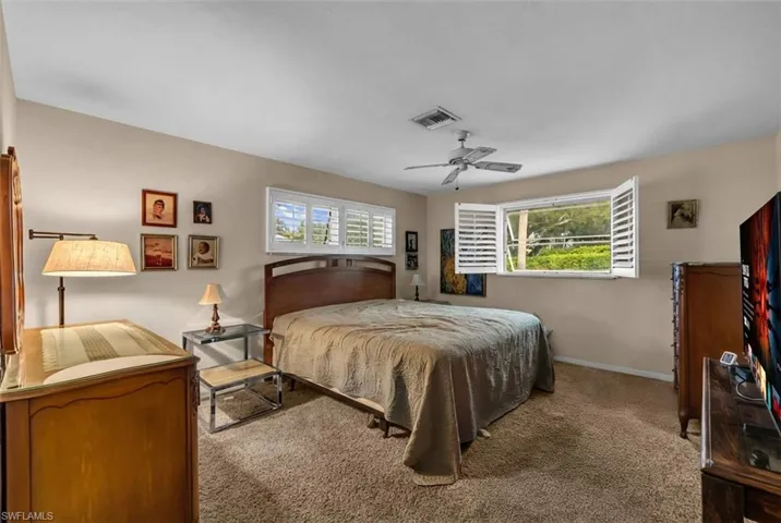 Carpeted bedroom featuring multiple windows and ceiling fan