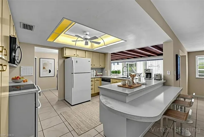 Kitchen with white appliances, a peninsula, healthy amount of natural light, and light countertops