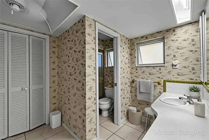 Full bath featuring wallpapered walls, a closet, vanity, and light tile patterned floors