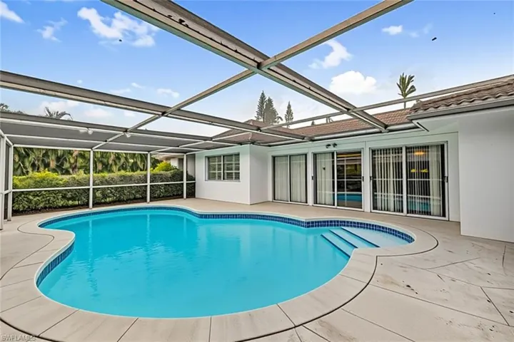 Swimming pool featuring a patio, glass enclosure, and a sunroom