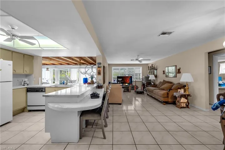 Kitchen with ceiling fan, light countertops, open floor plan, and white appliances