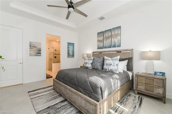 Bedroom with connected bathroom, ceiling fan, a raised ceiling, and crown molding