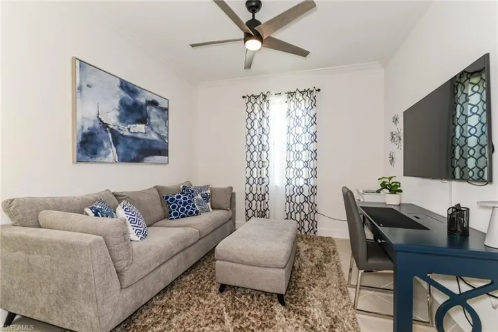 Living area featuring ornamental molding, a ceiling fan, and light tile patterned floors