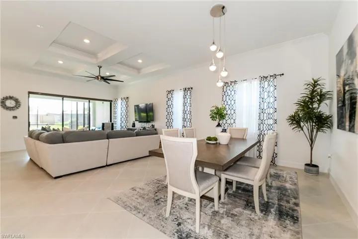 Dining space with coffered ceiling, plenty of natural light, beam ceiling, ceiling fan, and light tile patterned floors