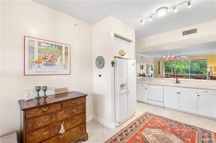 Kitchen with light tile patterned flooring, visible vents, white appliances, white cabinetry, and a sink