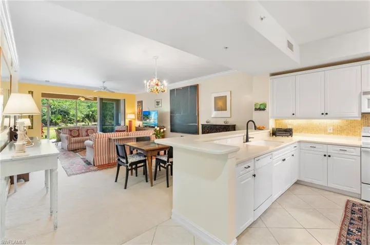 Kitchen featuring open floor plan, white appliances, a sink, light tile patterned flooring, and a peninsula