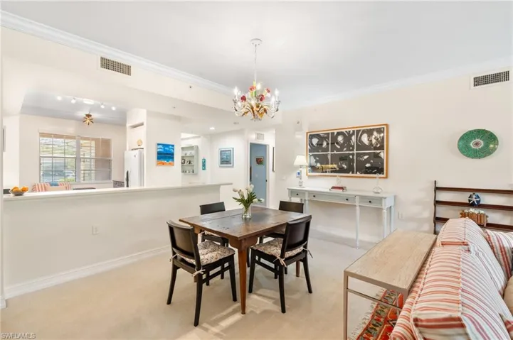 Dining area with ornamental molding, visible vents, an inviting chandelier, and light carpet