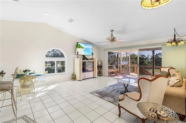 Living area featuring vaulted ceiling, plenty of natural light, a ceiling fan, and tile flooring